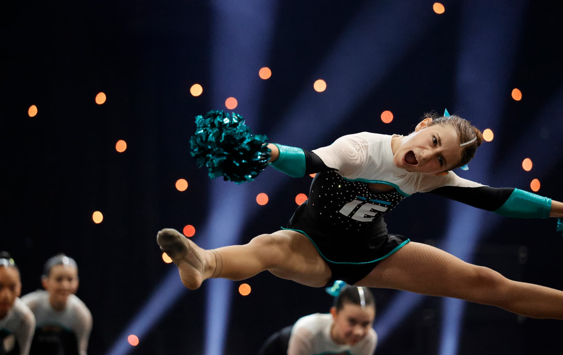 Cheerleader in salto con i pom-pom durante la routine